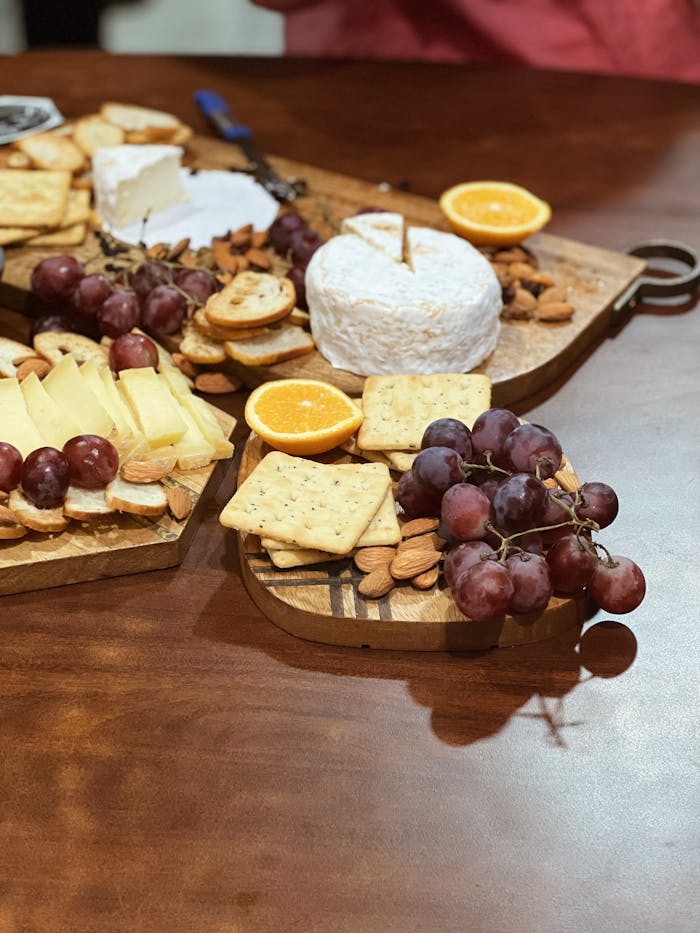 Delicious cheese platter featuring grapes, oranges, and crackers on a wooden board.