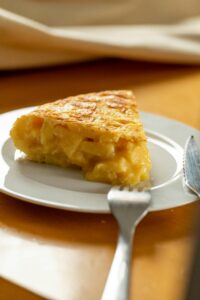 Appetizing Spanish omelette slice on a white plate, perfect breakfast dish.