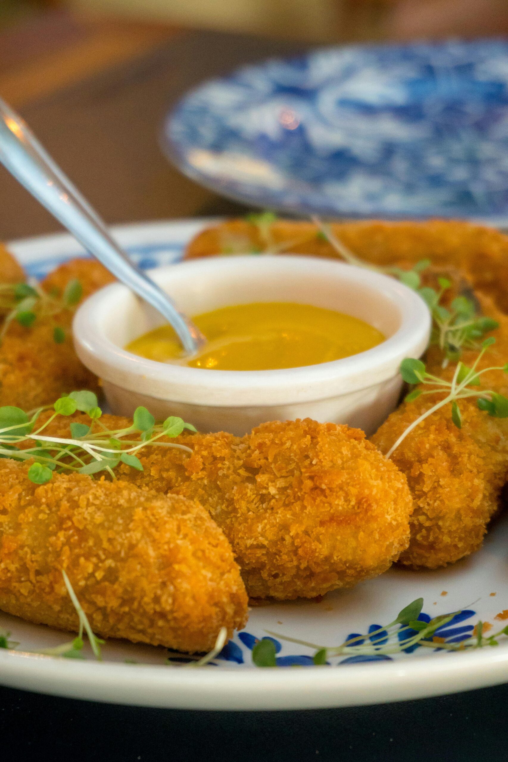 Delicious crispy potato croquettes served with a savory mustard dipping sauce, perfect for sharing.