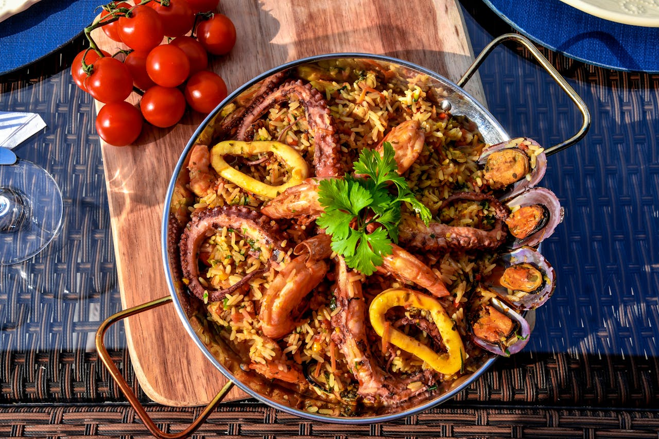 A vibrant seafood paella featuring octopus, shrimp, mussels, and fresh vegetables served outdoors.