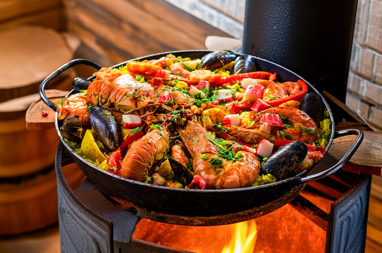Delicious seafood paella sizzling atop an open flame, filled with colorful ingredients.