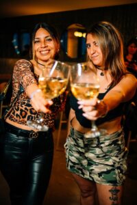 Two women enjoying a night out at a bar in Buenos Aires, toasting with wine glasses.