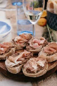 A delicious spread of charcuterie on rustic bread paired with a glass of white wine.