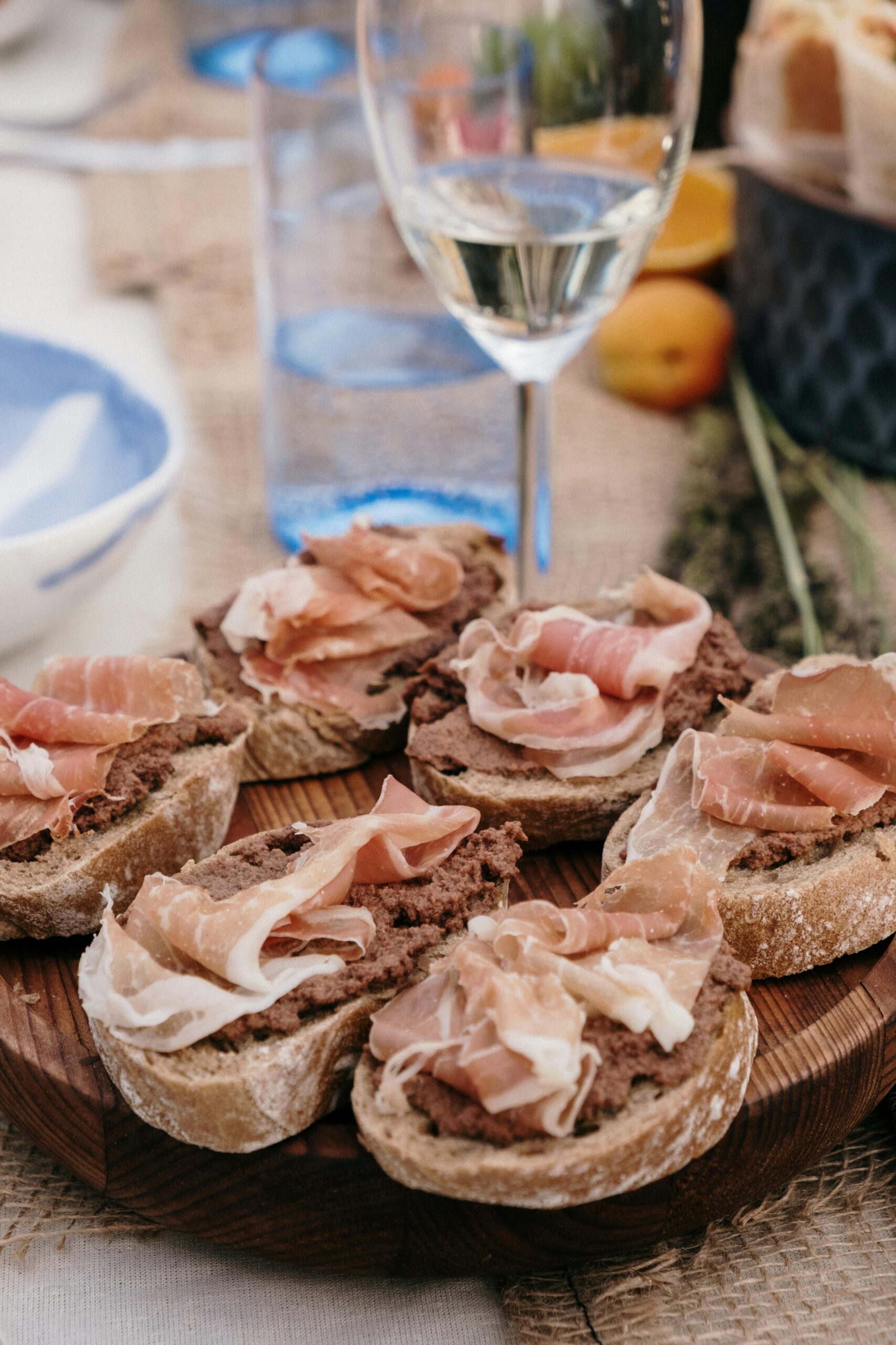 A delicious spread of charcuterie on rustic bread paired with a glass of white wine.