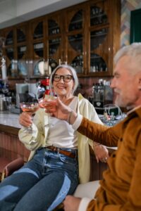 Happy senior couple toasting with wine glasses at a cozy indoor cafe setting.