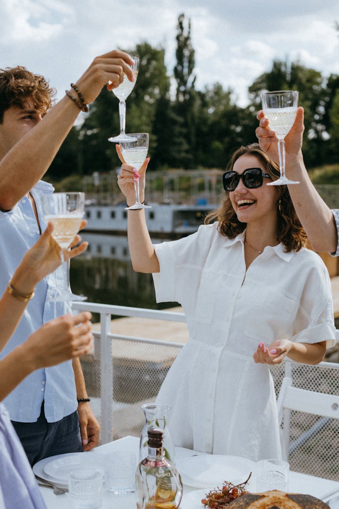Group of friends enjoying a joyful toast with wine glasses on a sunny day.